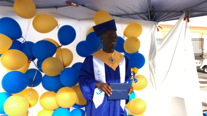 A DPS graduate poses with his diploma in front of balloons.